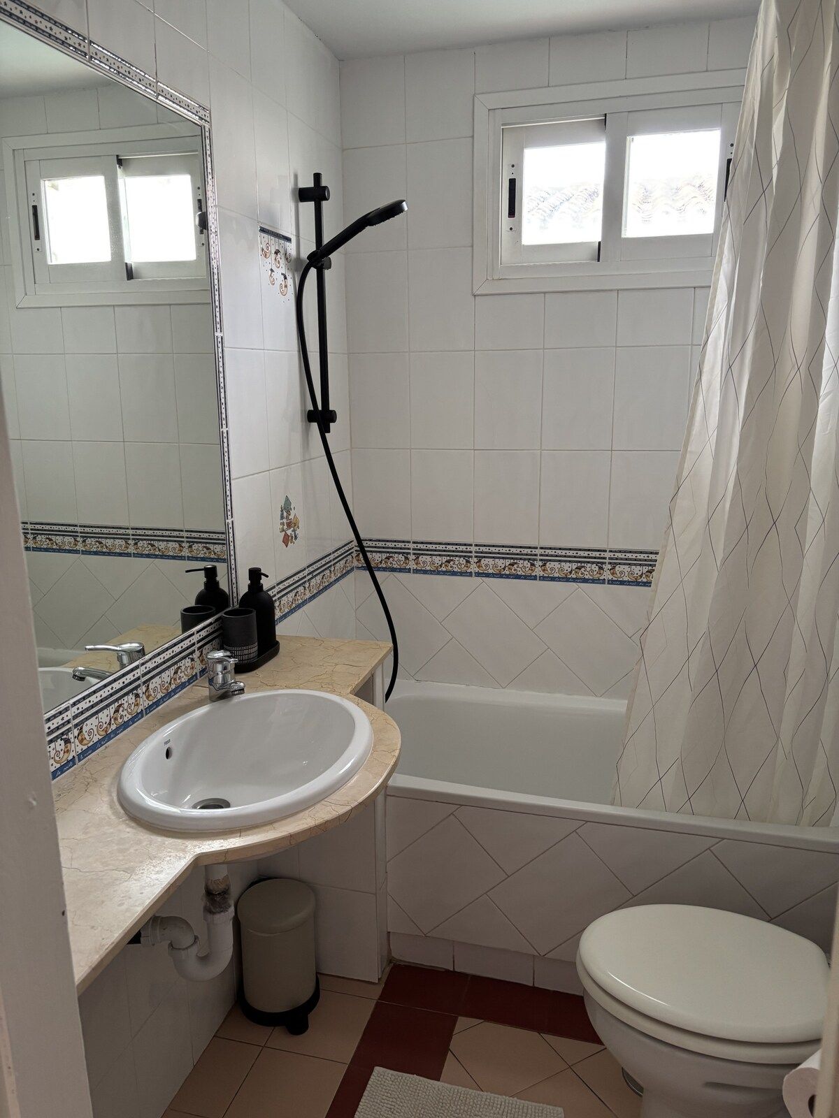 A bathroom with a white sink, a bathtub, a toilet, and a shower curtain.