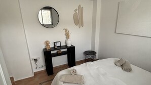 Ein Schlafzimmer mit einem Bett, einem Nachttisch, einem Spiegel und einem Wandbild.