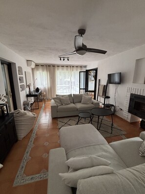 Una sala de estar con sofá, mesa de centro, televisor y chimenea.