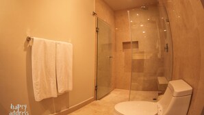 A modern bathroom with a glass-enclosed shower, a toilet, and a towel rack. - Luxurious 2BR Condo surrounded by nature by Happy Address (Playa del Carmen)