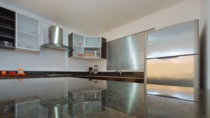 Una cucina moderna con frigorifero in acciaio inossidabile, forno integrato e isola con piano in vetro.
