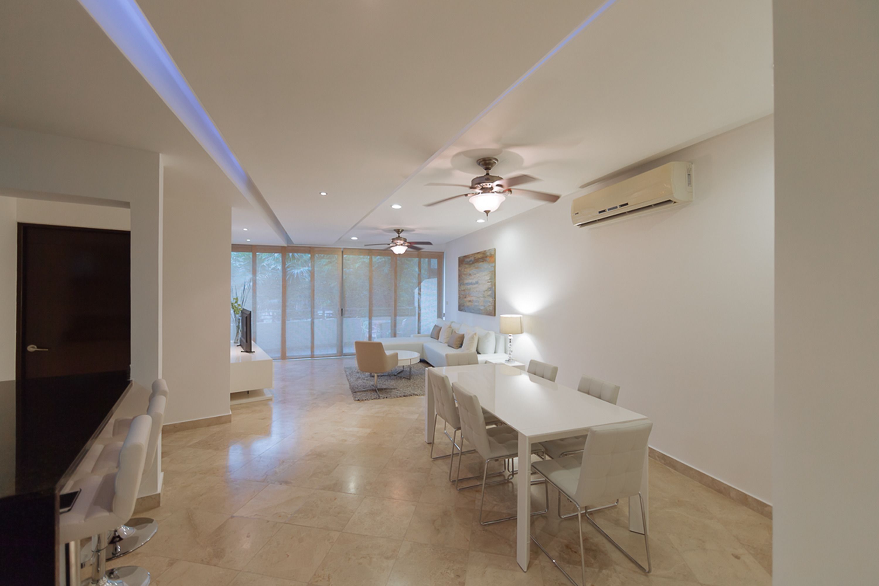 A spacious living area with a dining table, sofas, and a TV.