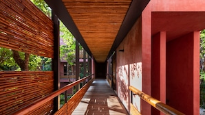 A corridor with wooden railings and a red wall. - Delightful and Quiet 2 BR Condo in Tulum by Happy Address (Tulum)