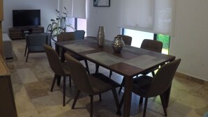 A dining area with a table and chairs, a television, and a ceiling fan. - Delightful and Quiet 2 BR Condo in Tulum by Happy Address (Tulum)
