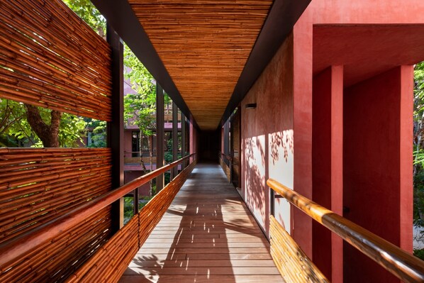 A corridor with wooden railings and a red wall.