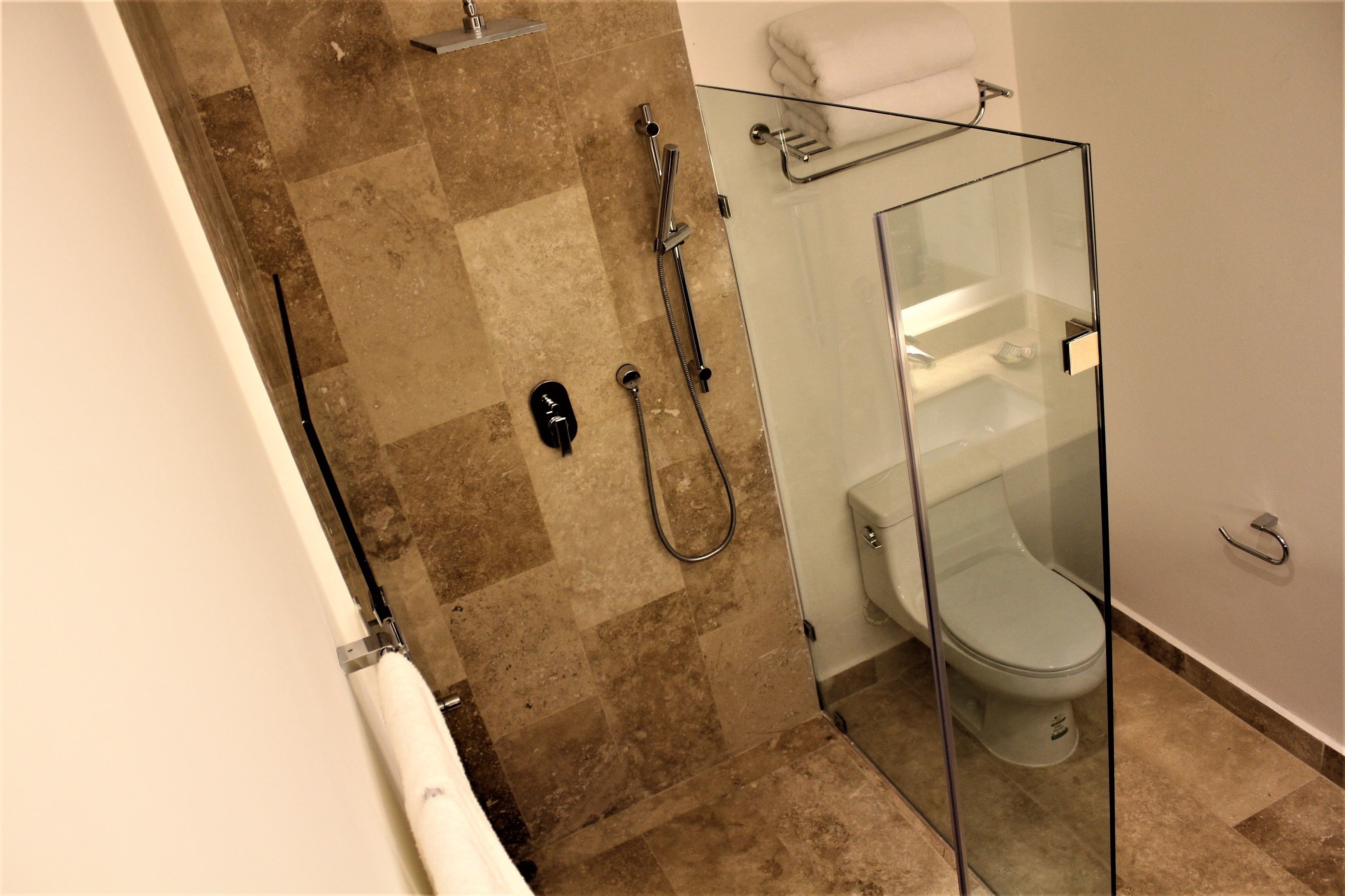 Ein modernes Badezimmer mit einer gläsernen Dusche, einer weißen Toilette und einem Handtuchhalter.