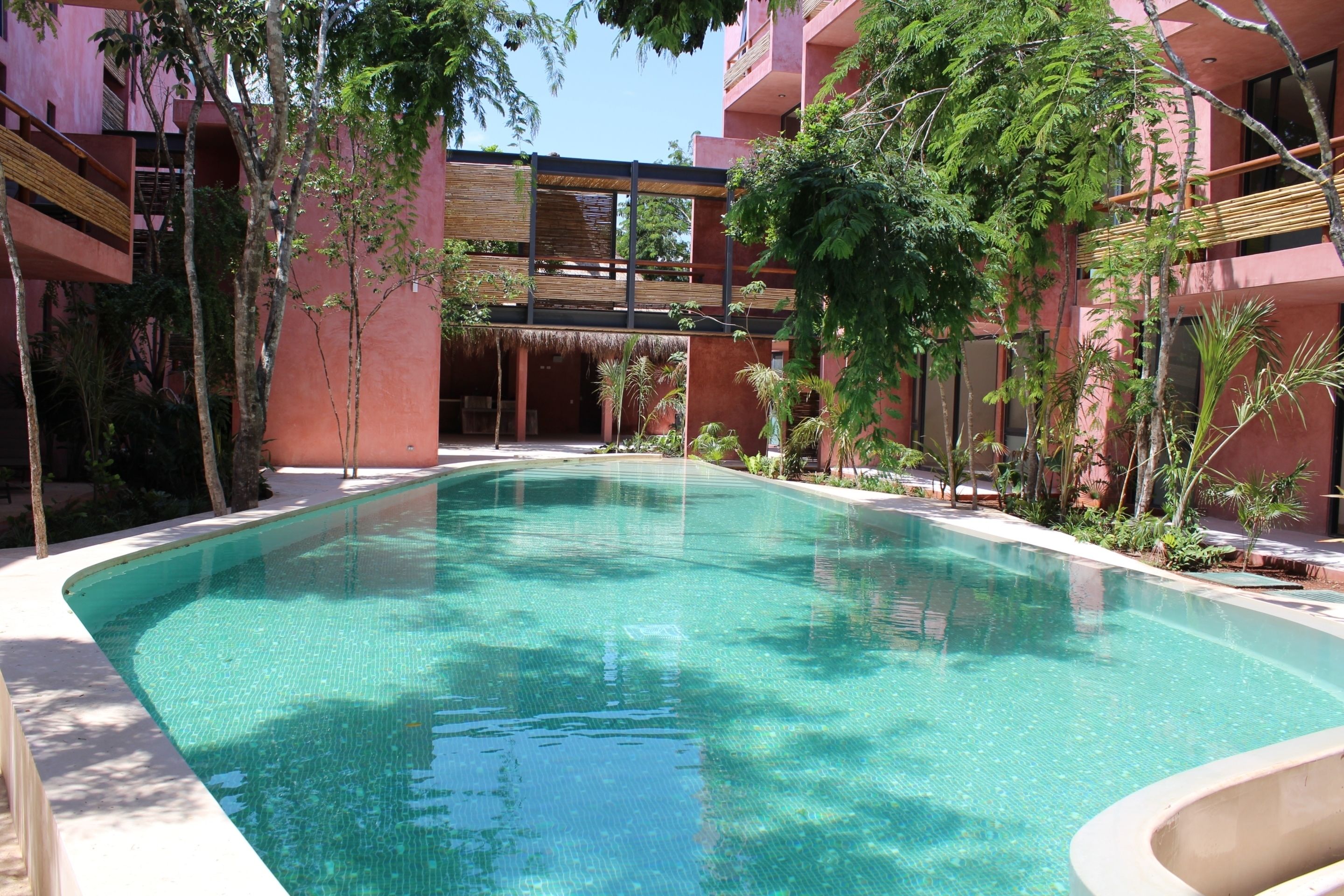 Ein Pool, umgeben von Bäumen und einem Gebäude mit Balkonen.