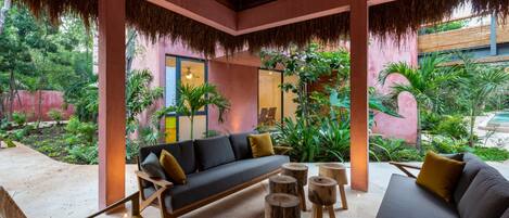 Un espacio lounge moderno al aire libre con sofá, sillas y taburetes de madera.