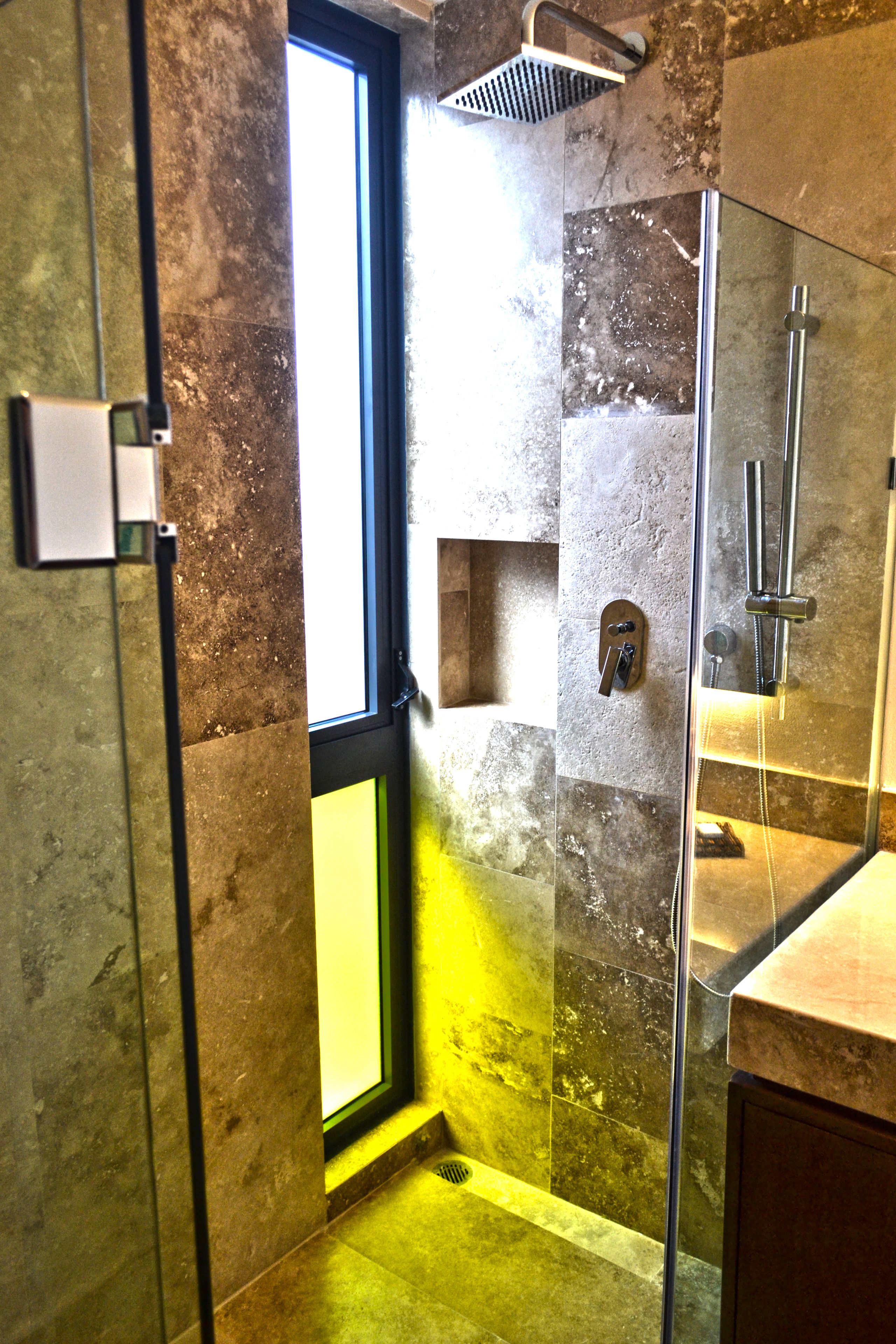 Une salle de bain avec une douche à l’italienne (ou douche à parois de verre), une porte visible et un sol carrelé.