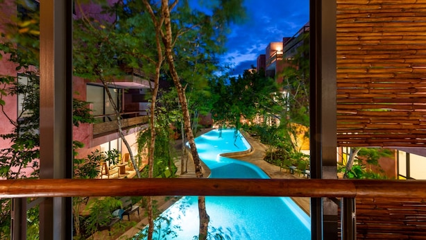 Un espace piscine au design incurvé, entouré d’arbres et de bâtiments.
