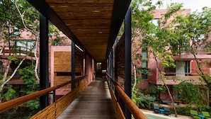 Une passerelle en bois offrant une vue sur un bâtiment et la verdure environnante.