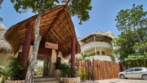 Un complexe hôtelier doté d’une structure à toit de chaume, d’une enseigne indiquant « LIRIA » et d’une voiture garée devant.