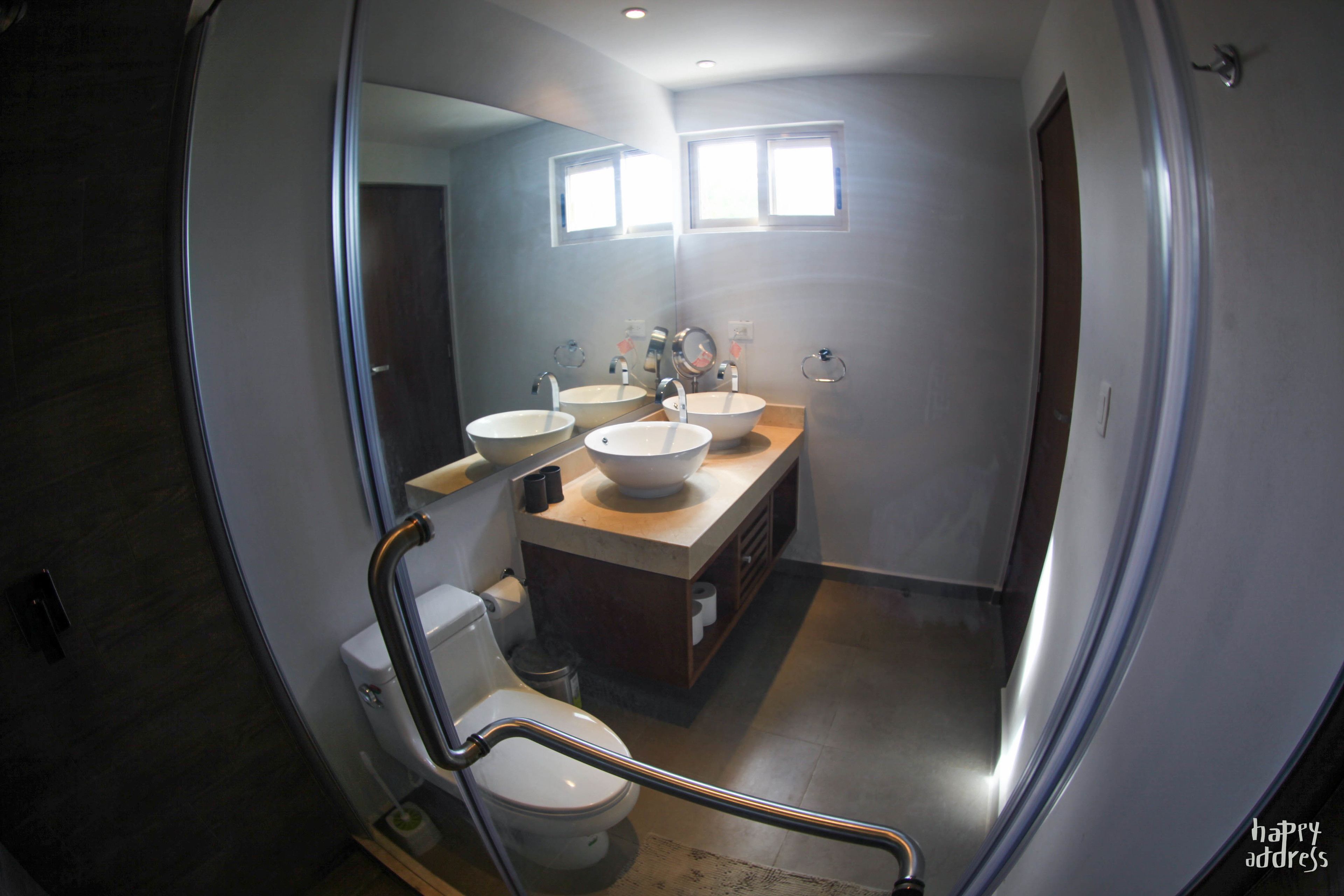 Un baño moderno con dos lavamanos, un inodoro y una ducha.