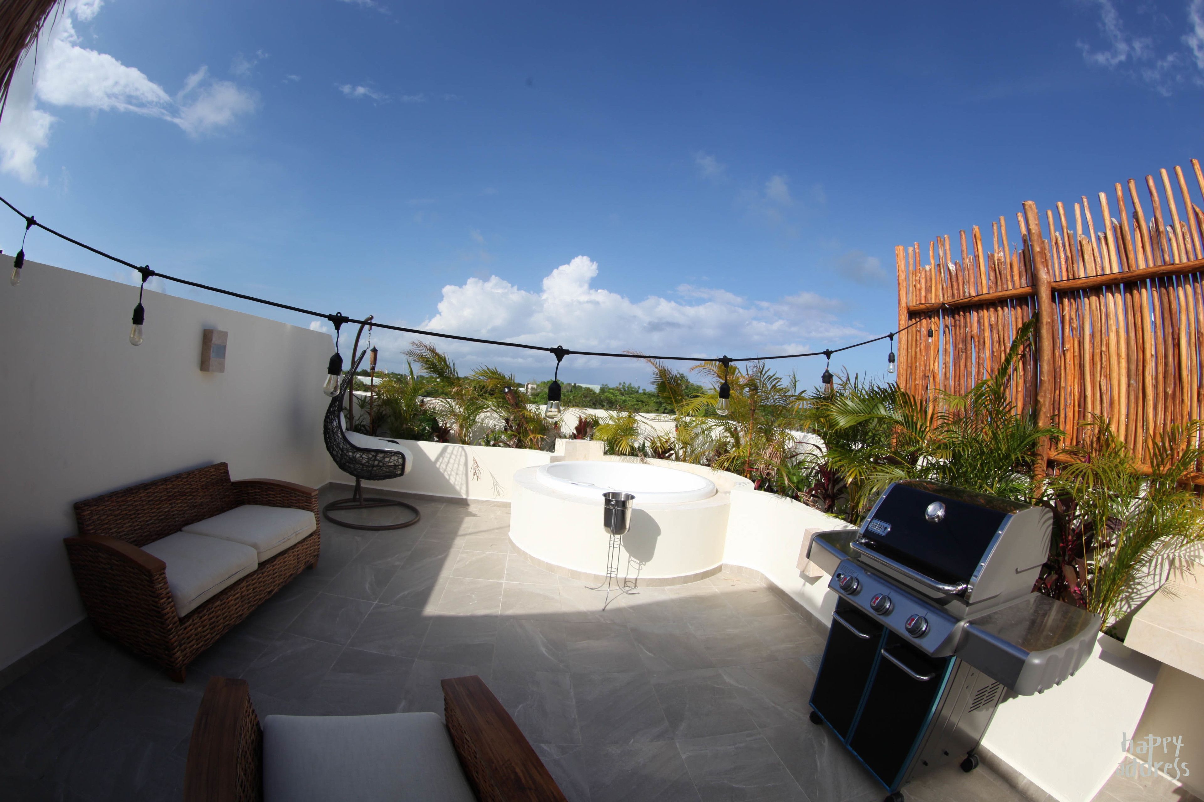 Une terrasse extérieure équipée d’un barbecue, d’un canapé et d’un jacuzzi.