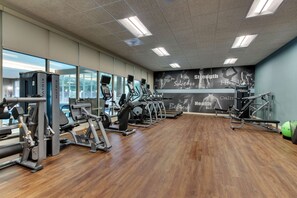 Un gimnasio con máquinas de cardio, equipo de entrenamiento de fuerza y una pared motivacional.