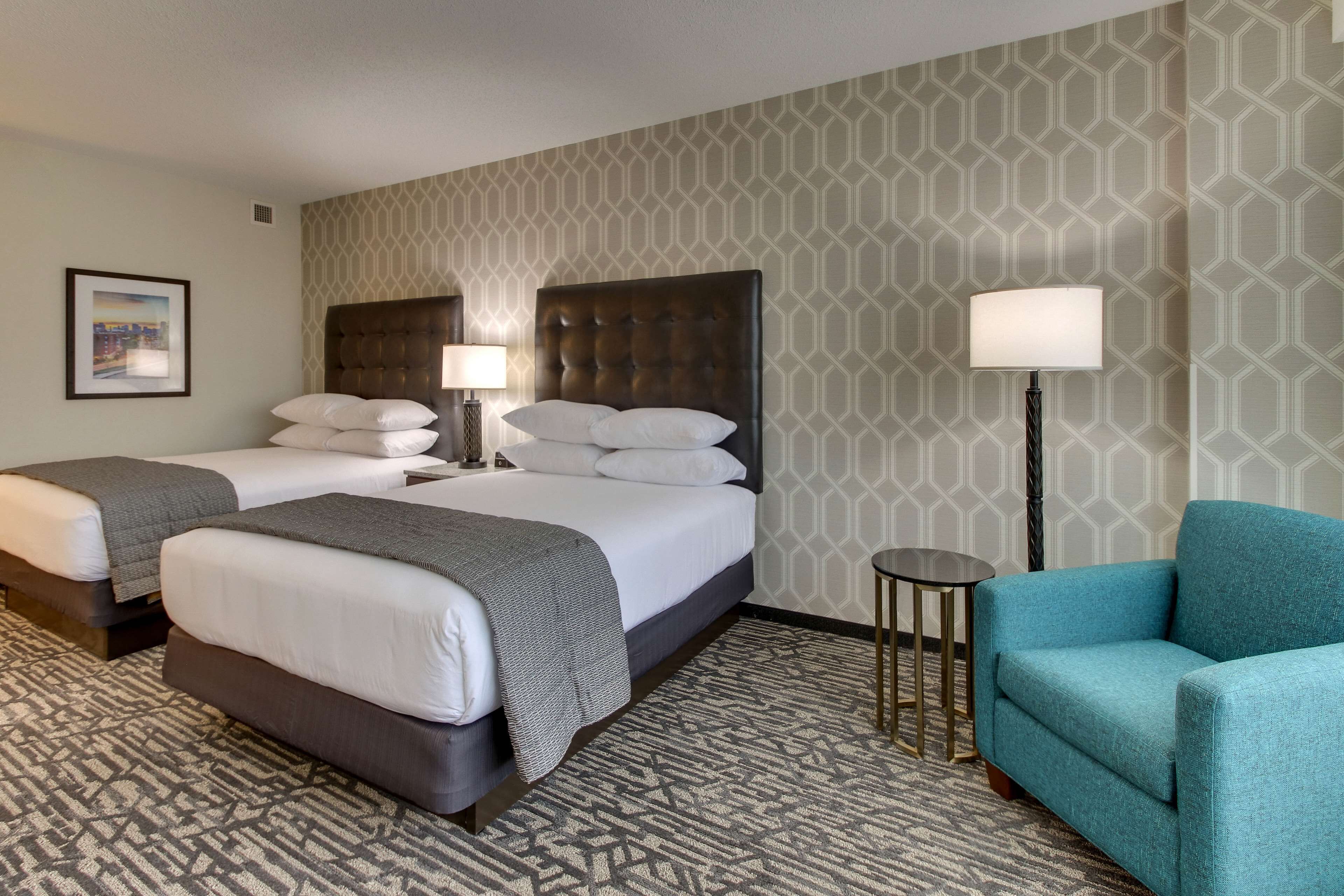 A hotel room with two beds, a sofa, a small table, and a lamp.