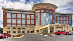 Un hotel Drury Plaza con un diseño arquitectónico moderno, que presenta una entrada curva y amplios ventanales.