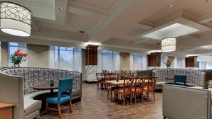 Un restaurante moderno con una zona de asientos curva, mesas y sillas de madera.