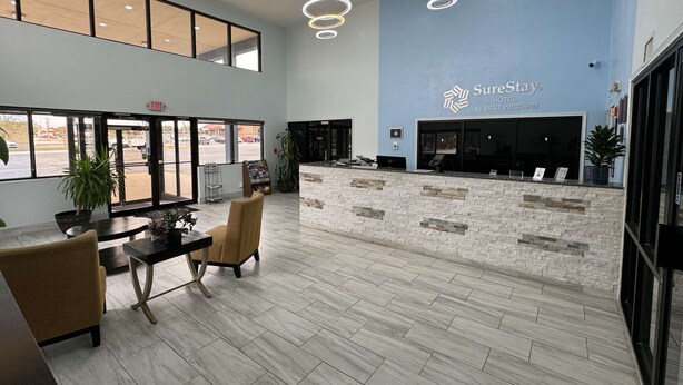 A hotel reception area with a modern design, featuring a reception desk, seating area, and large windows providing views of the parking lot. - SureStay Hotel by Best Western Childress (Childress)