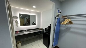 A modern bathroom with a large mirror, a sink, a black cabinet, a towel rack, and a blue shower curtain. - SureStay Hotel by Best Western Childress (Childress)