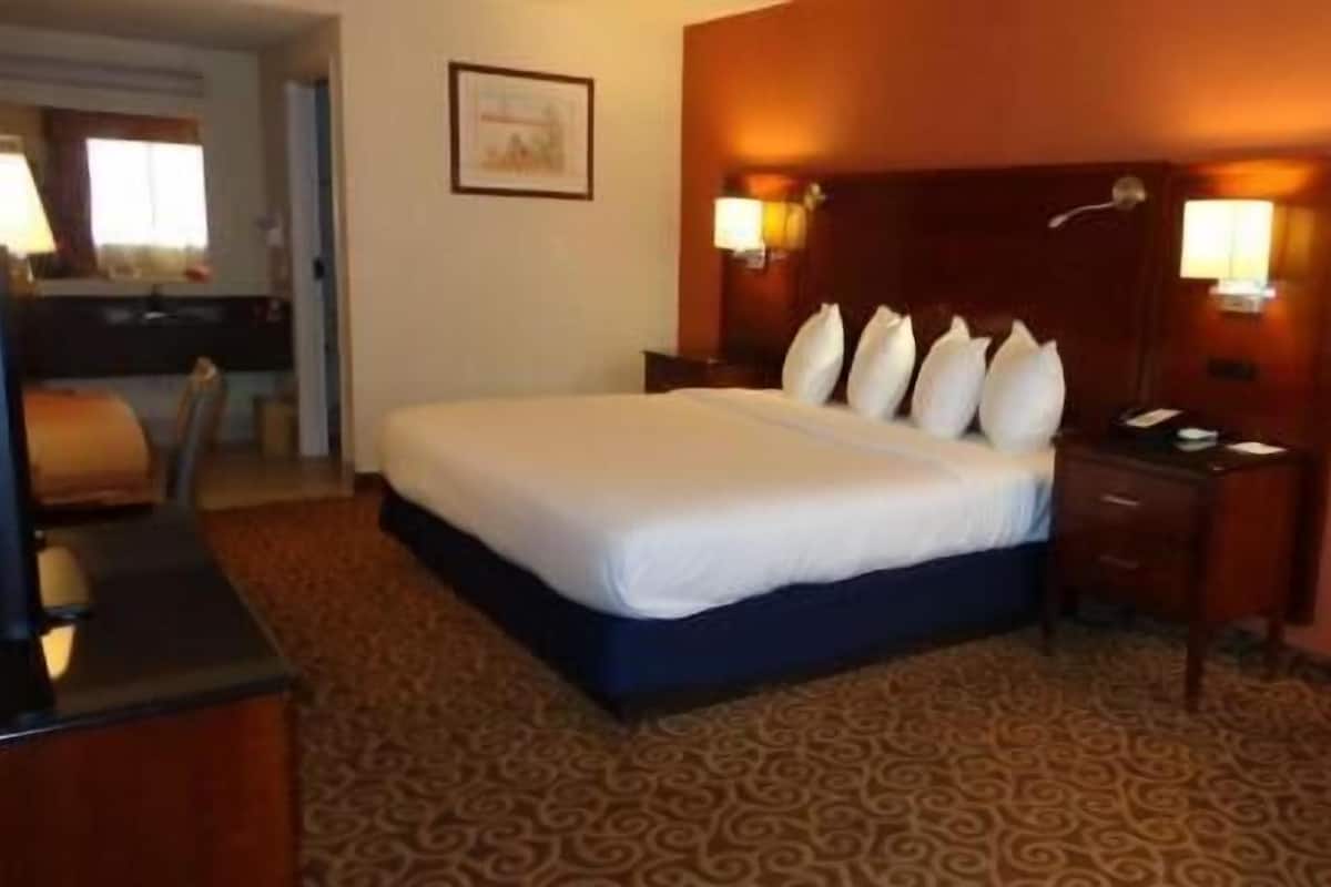 Ein Hotelzimmer mit einem großen Bett, einem Schreibtisch, einem Stuhl und einer Lampe.