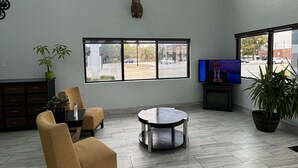 A spacious living area with high ceilings, large windows, a mounted deer head, a television, and a dining table with chairs. - SureStay Hotel by Best Western Childress (Childress)