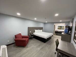 Ein Hotelzimmer mit einem Bett, einem Schreibtisch, einem Stuhl, einem rot gepunkteten Ohrensessel und einem kleinen Tisch.