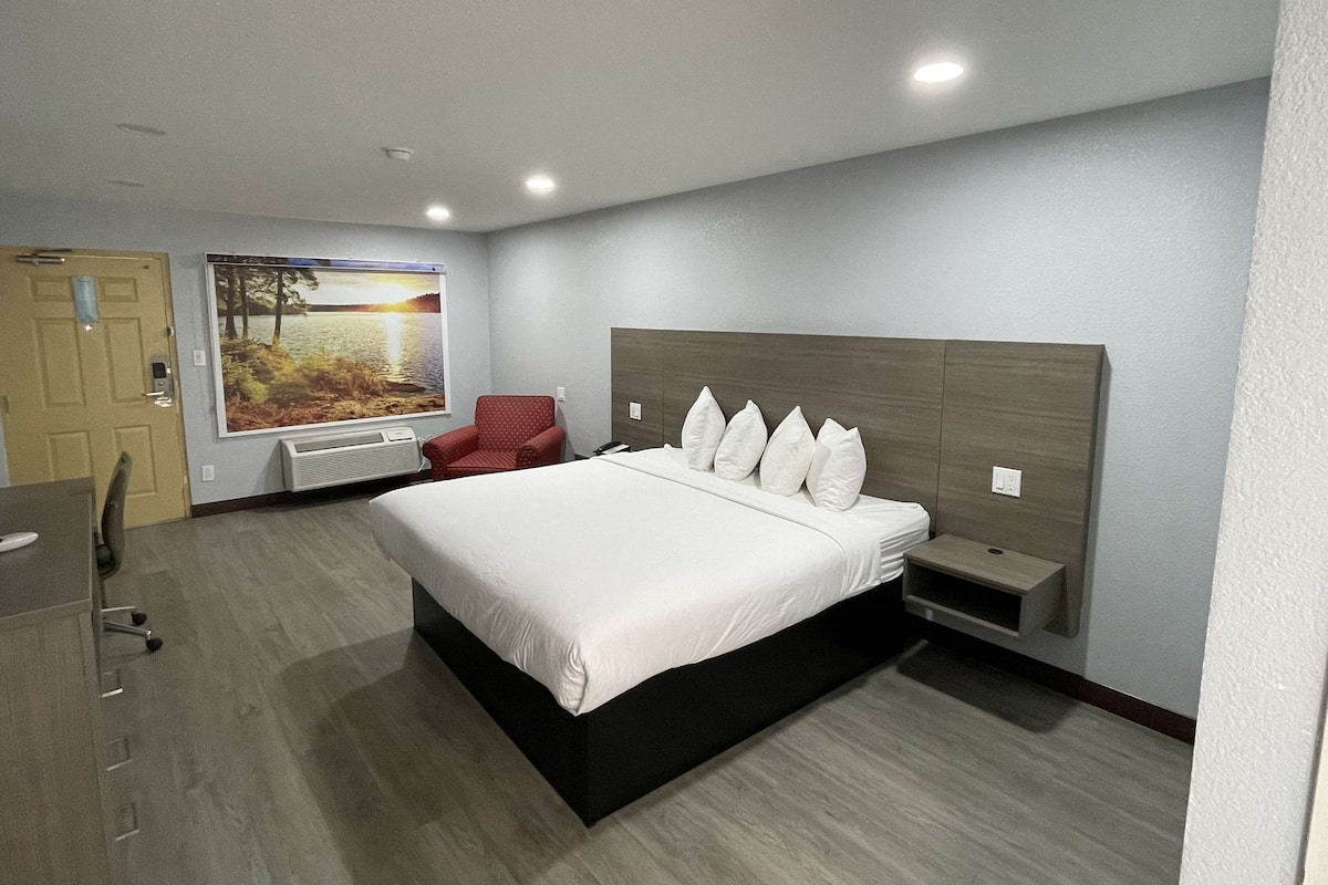 Ein Hotelzimmer mit einem großen Bett, einem Schreibtisch, einem Stuhl und einem großen Fenster mit schöner Aussicht.