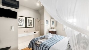 Une chambre à coucher avec un lit, une grande fenêtre avec des rideaux légers, une douche et un téléviseur fixé au mur.