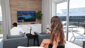A modern hotel room with a large TV, a balcony with a view, and a plant. - Palapa Suite # 5, walk to Eagle Beach (Eagle)