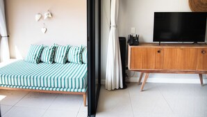 A room with a striped sofa, a wooden cabinet with a TV, and a wall-mounted light fixture.