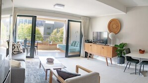 A modern living room with a sofa, a coffee table, a TV, and a dining area with a table and chairs.
