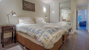 A bedroom with a large bed, bedside lamps, a wooden nightstand, and a mirror. - 2bdr villa in Dunsborough (Dunsborough)