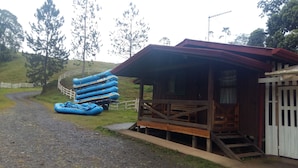A rustic cabin with a wooden porch and a gravel path leading to it. - Finca Tres Equis - Farm and Forest (Turrialba)