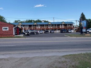 A motel with a row of rooms, a parking lot, and a small adjacent building.