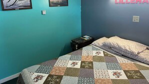 A bedroom with teal walls, a quilted bedspread, two framed pictures, and a 'LILLEHA' sign. - Norway Inn (Jamestown)