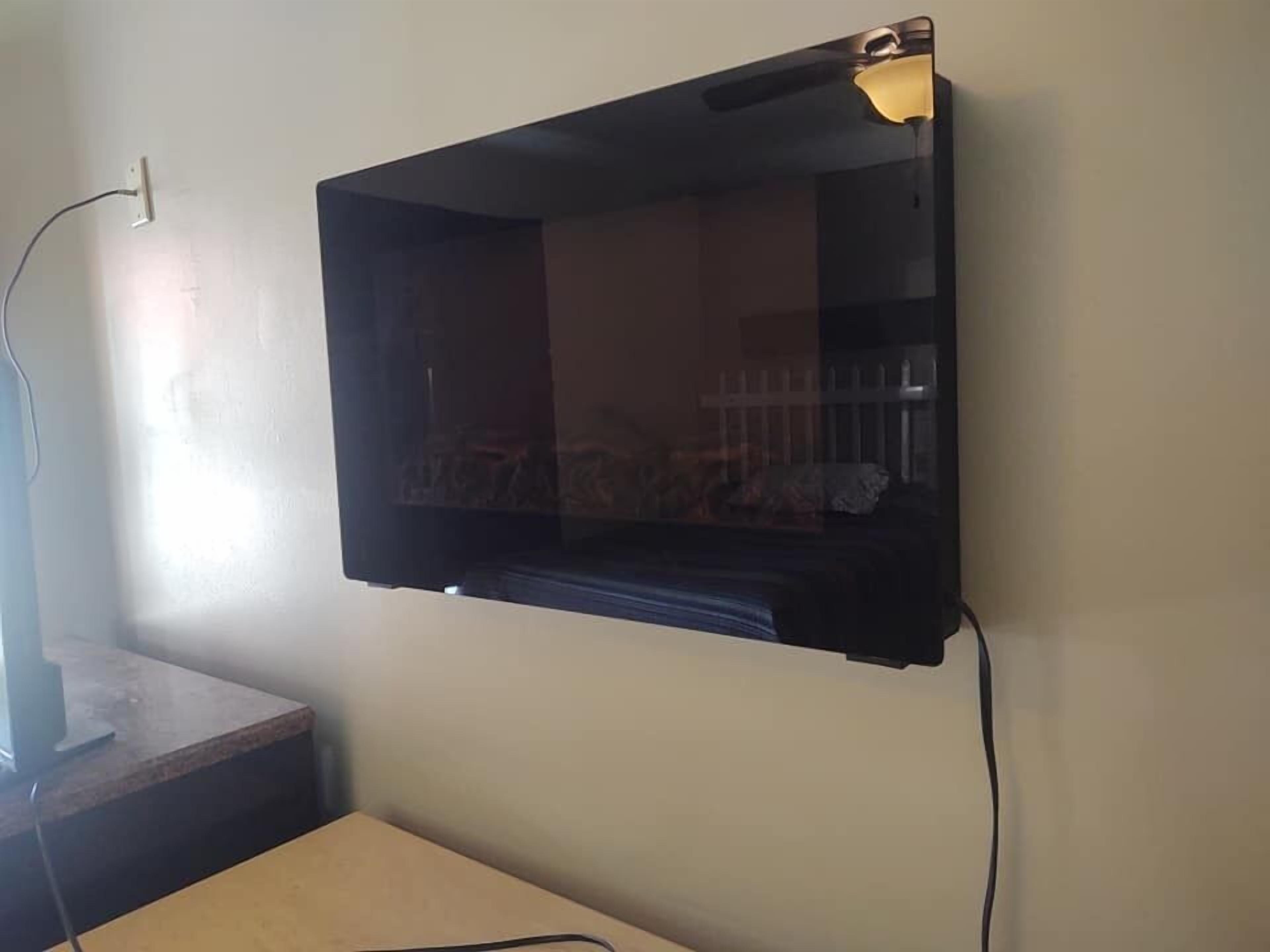 A flat-screen TV mounted on a wall with a cable connected to it.