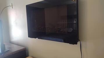 A flat-screen TV mounted on a wall with a cable connected to it.