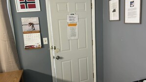 A door with a sign, a calendar, and two framed items on the wall. - Norway Inn (Jamestown)