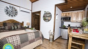 A bedroom with a bed, a wall clock, and a bedside table with a lamp.