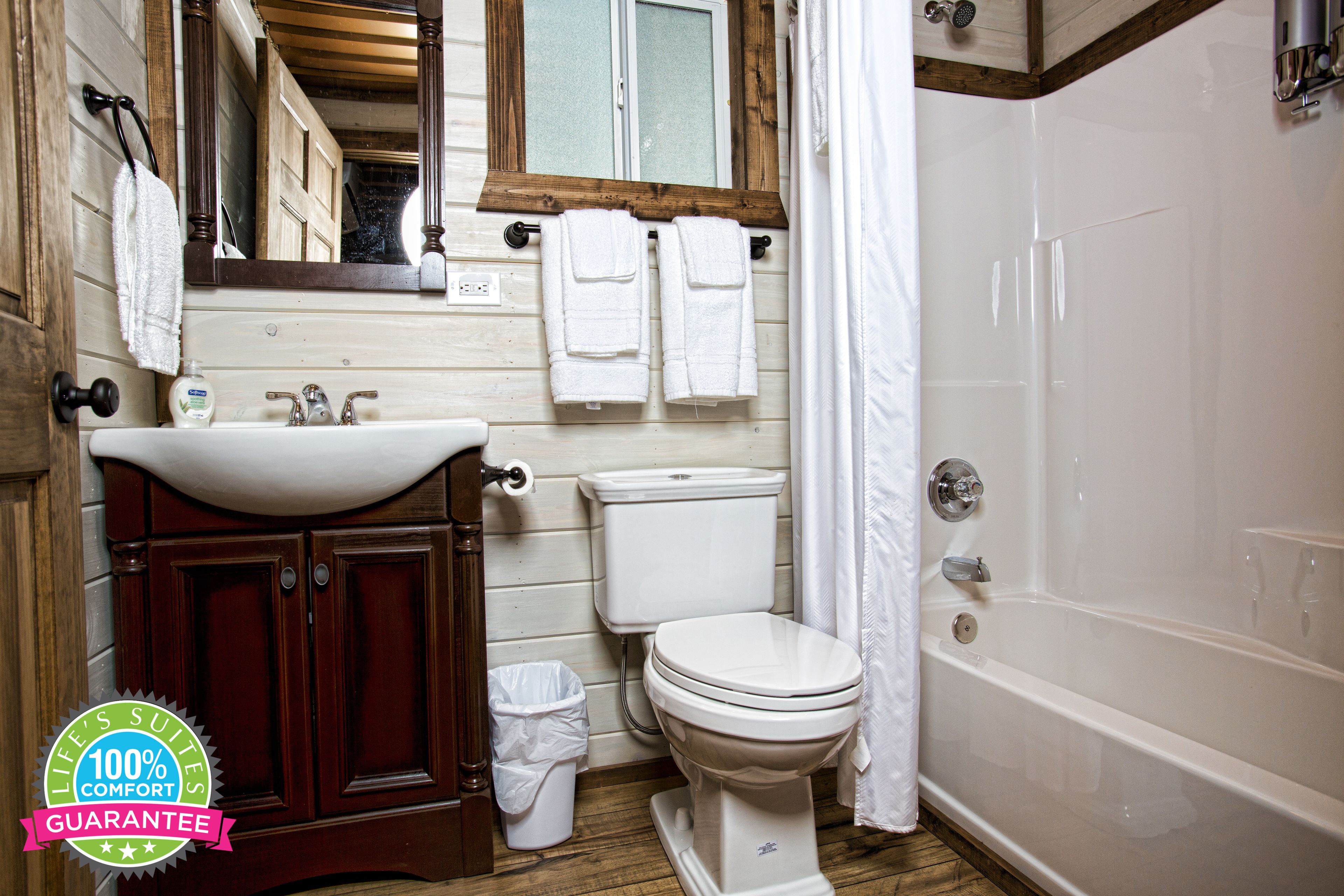 Un baño con tocador de madera, inodoro y bañera.