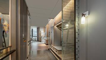 A hotel corridor with a modern design, including a glass partition, a reception desk, and a seating area.