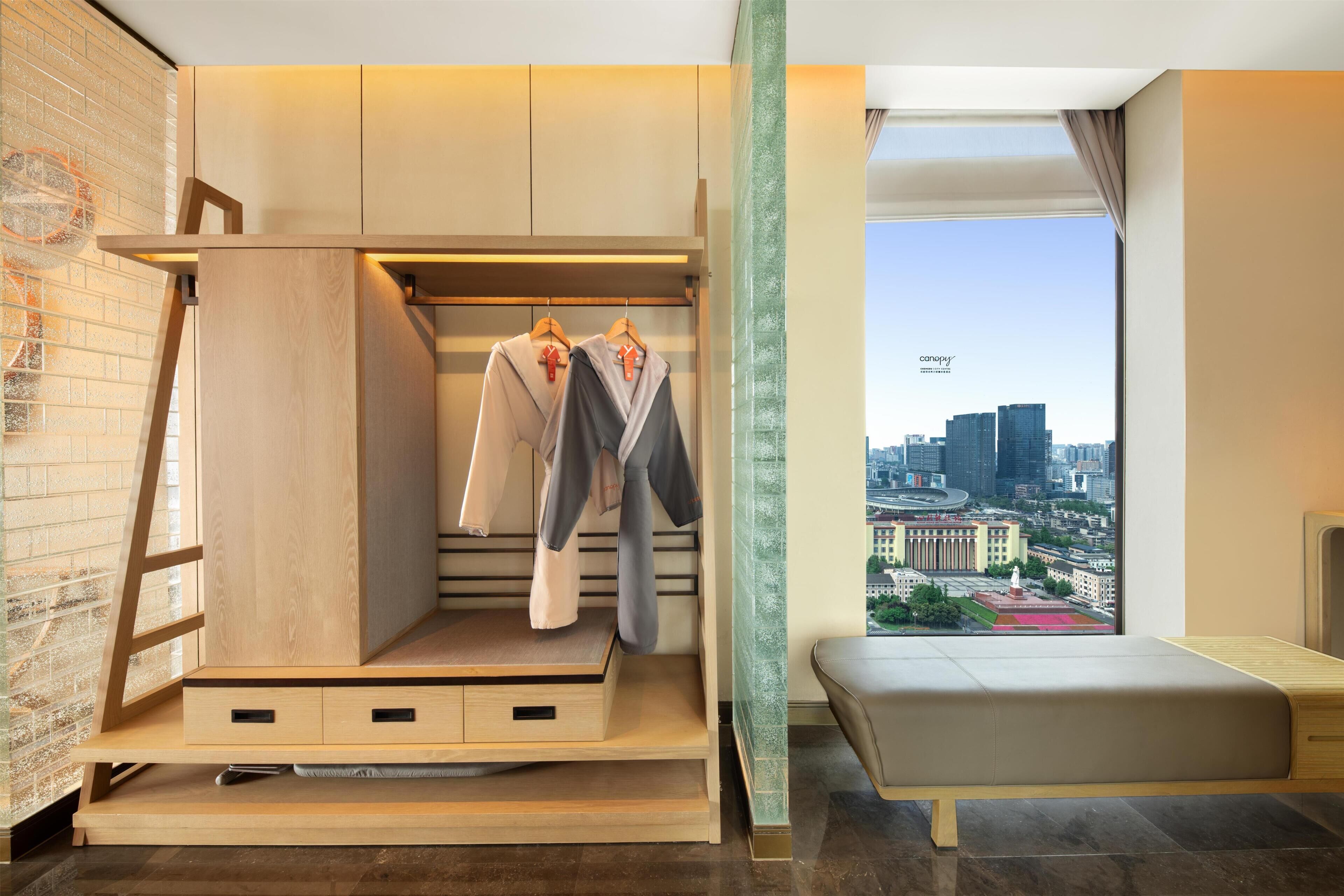 A modern room with a built-in wardrobe, a bench, and a city view.