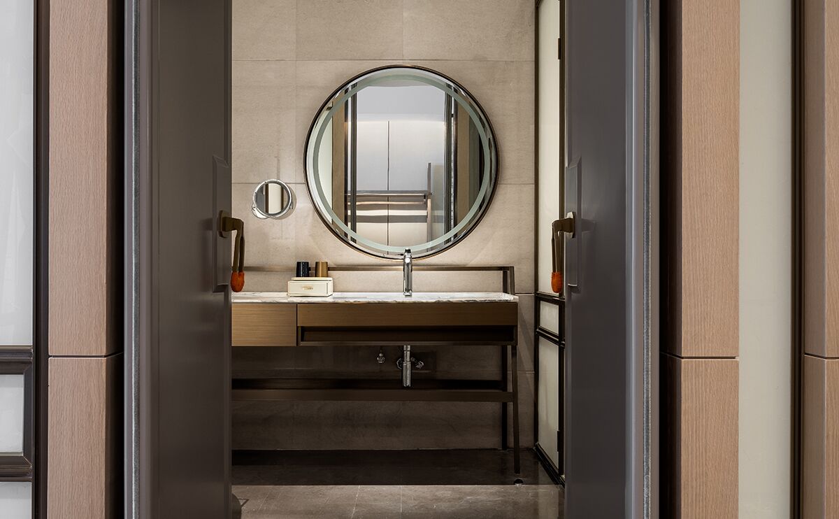 A modern bathroom with a round mirror, a sink, and a cabinet.