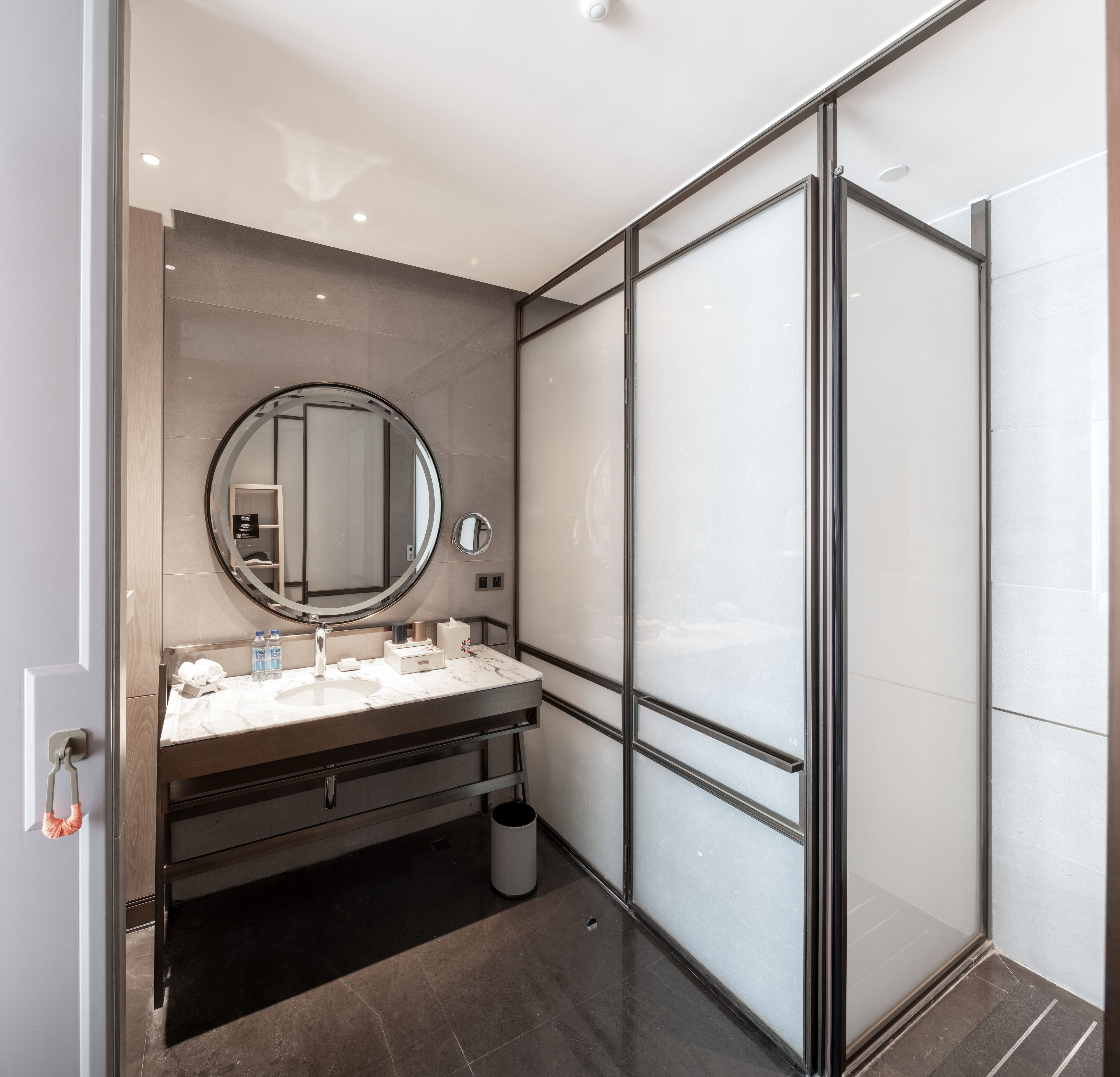 A modern bathroom with a large mirror, a sink, and a glass shower enclosure.