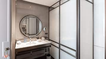 A modern bathroom with a large mirror, a sink, and a glass shower enclosure.