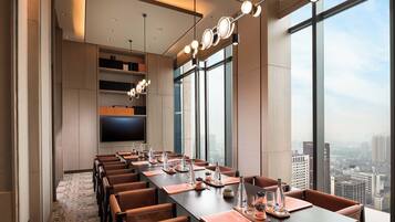 A conference room with a long table, chairs, and a city view through large windows.