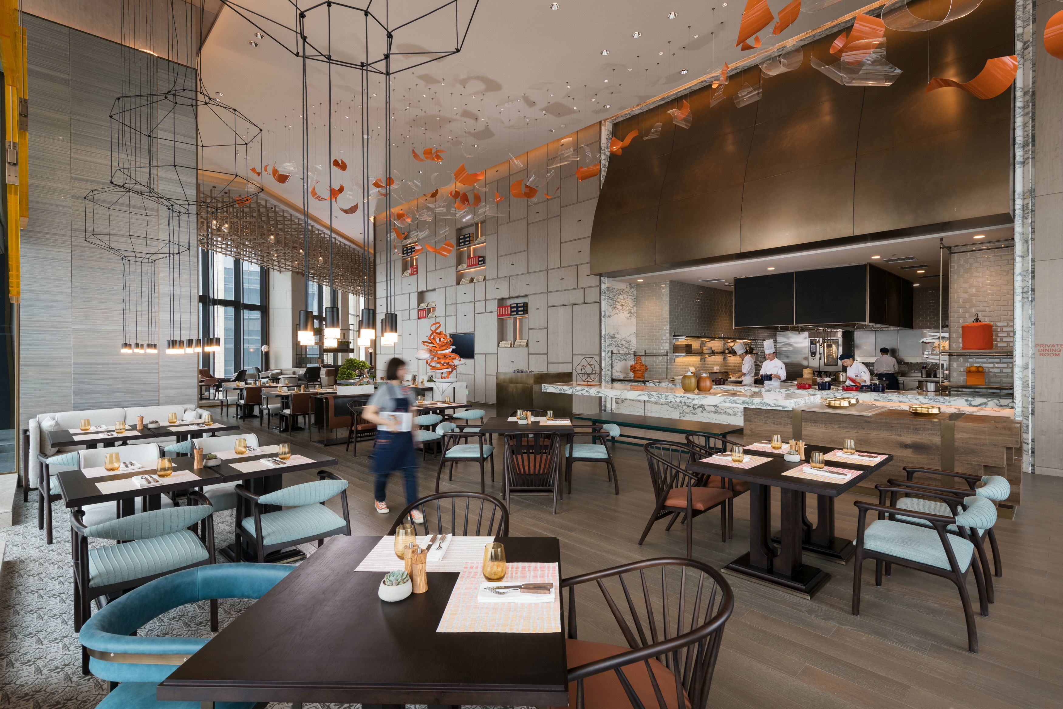 Un restaurant moderne doté de plusieurs espaces de restauration, d’une cuisine et d’un bar.