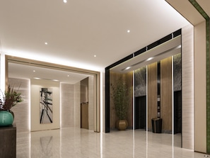 Eine moderne Lobby mit poliertem Boden, einer großen Topfpflanze, einem gerahmten Kunstwerk und einem Empfangsbereich.
