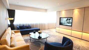 A modern living room with a sofa, armchair, coffee table, and a TV mounted on the wall.